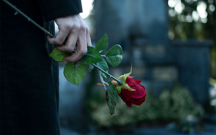 Jemand steht mit einer Rose in der Hand