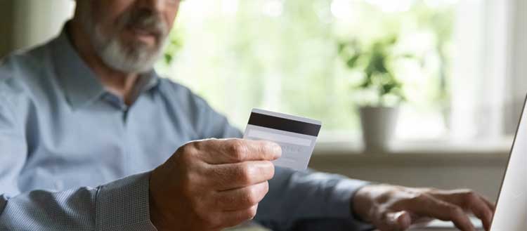 Mann mit Kreditkarte in der Hand am Computer