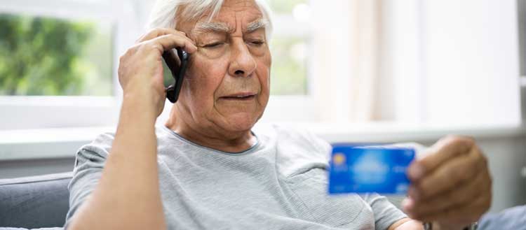 Mann am Telefon mit Debitkarte